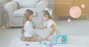 Two young girls are playing with colorful toys on the floor, smiling and enjoying their time together.